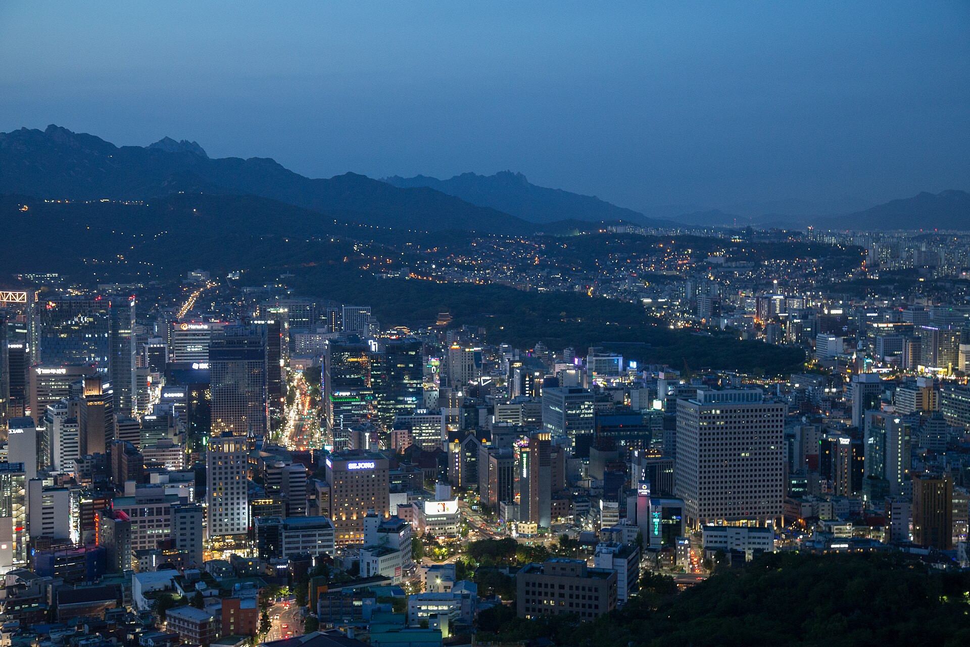 首尔城市天际线全景，现代高楼与远山轮廓交织，汉江隐于城市腹地